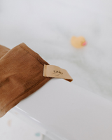 Serviette de bain à capuche ultra douce couleur santal sur le rebord du bain.