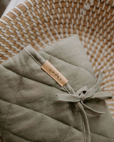 Tapis à langer couleur sauge dans un panier et détails.