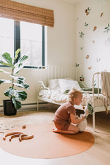 Enfant qui joue sur un tapis de cuir végan rond côté tan.