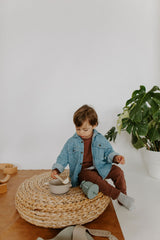 Enfant qui joue avec vaisselle en silicone couleur grège.